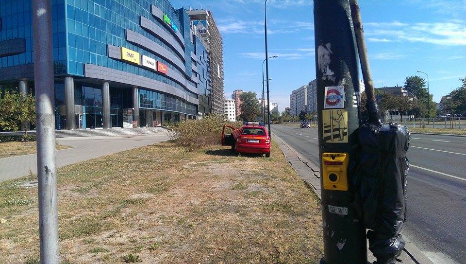 Czerwony samochód ZTM, który stoi po drugiej stronie przystanku i którego najwyraźniej nie obowiązują przepisy ruchu drogowego.
