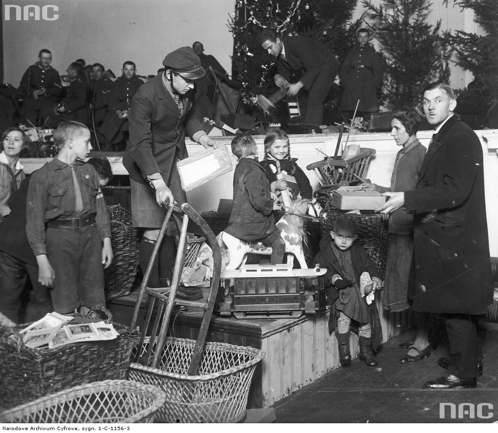 Rozdawanie zabawek dzieciom biorącym udział w wigilii dla bezrobotnych. W głębi widoczna orkiestra wojskowa 31 p.p. Fot. Narodowe Archiwum Cyfrowe