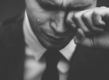 Mężczyzna w garniturze ociera łzę.