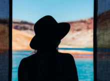 Kobieta w drzwiach, za nią obraz wyspy.