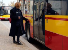 Kobieta naciska przycisk, by wsiąść do warszawskiego autobusu.