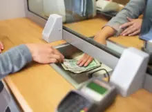 Kobieta wpłaca pieniądze w okienku. Fot. Shutterstock / Warszawa w Pigułce.
