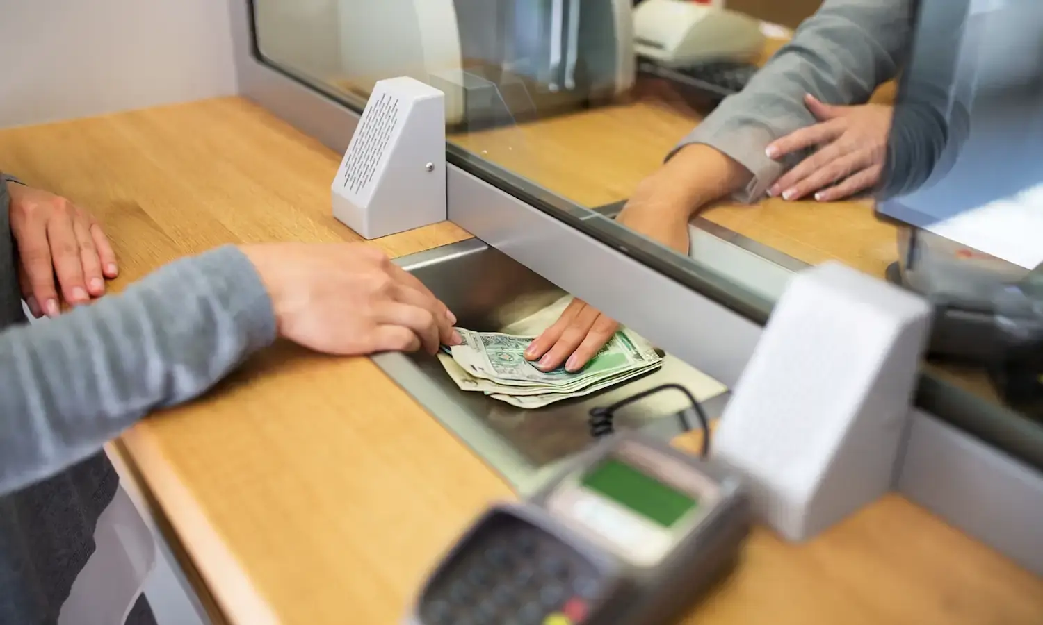 Kobieta wpłaca pieniądze w okienku. Fot. Shutterstock / Warszawa w Pigułce.