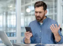 Zdziwiony mężczyzna spogląda na smartfona.