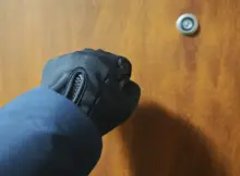 Mężczyzna w rękawiczkach i kurtce pukający do drzwi mieszkania. Fot. Warszawa w Pigułce