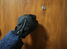 Mężczyzna w rękawiczkach i garniturze pukający do drzwi mieszkania. Fot. Warszawa w Pigułce