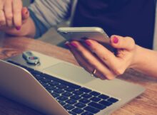 Kobieta pracująca przy laptopie, trzymająca w ręku telefon. Fot. Pixabay