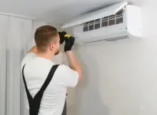 Technik montuje klimatyzację na ścianie budynku.