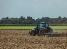 Rolnik w ciągniku wykonuje prace na polu.