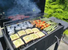 Grill na działce z kromkami chleba, szaszłykami, kiełbasami, ziemniakami i szparagami.