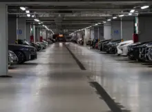Parking podziemny. Na zjęciu widać garaż oraz zaparkowane samochody.